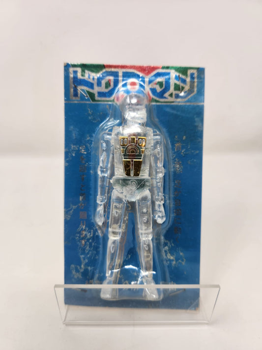 トクロマン (TOKUROMAN) — "SKULL MICROMAN" — パチモン / Knockoff Era Shōwa — Clear Crystal Body — Pechera Dorada Metálica — Cardback Azul Original — c. 1974–1980s — Made in Japan